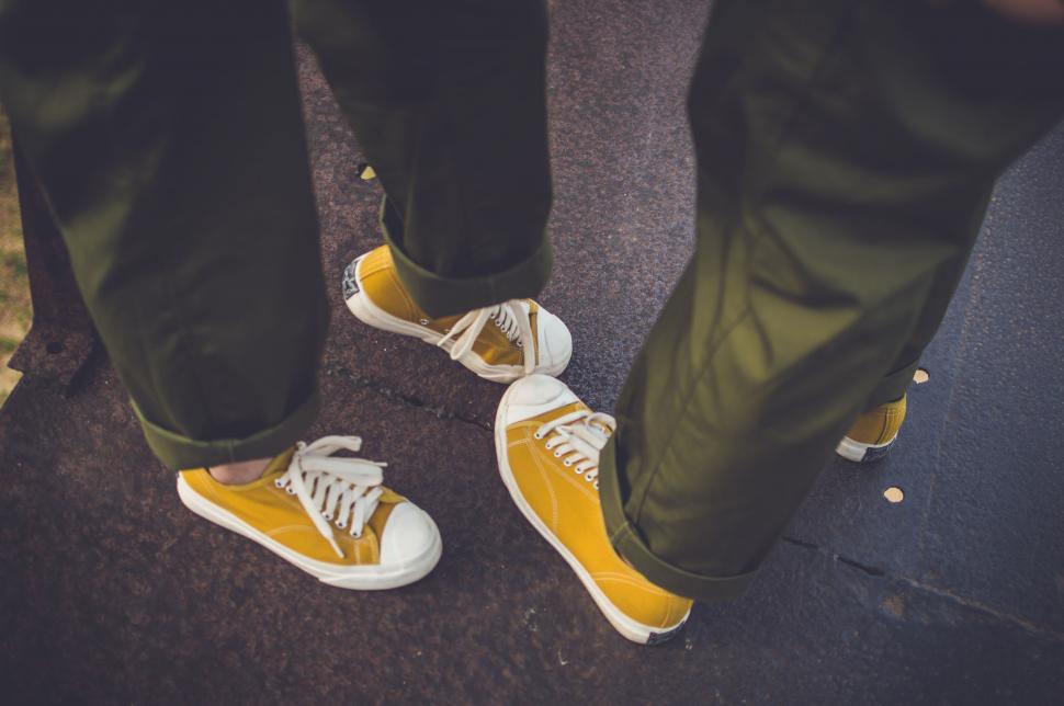 Free Image of Two People Feet with yellow canvas shoes  