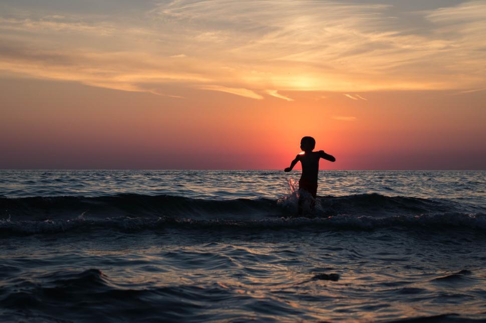 Free Image of Boy in Ocean during Sunset  