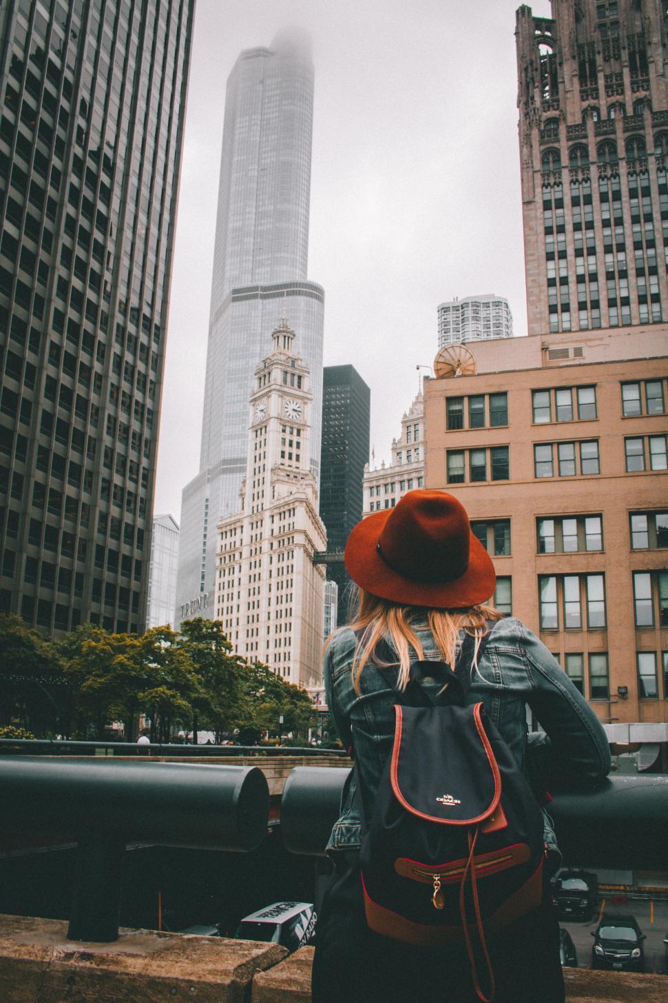 Free Image of Back View of Woman in Red Hat and denim jacket with city buildings in fog  