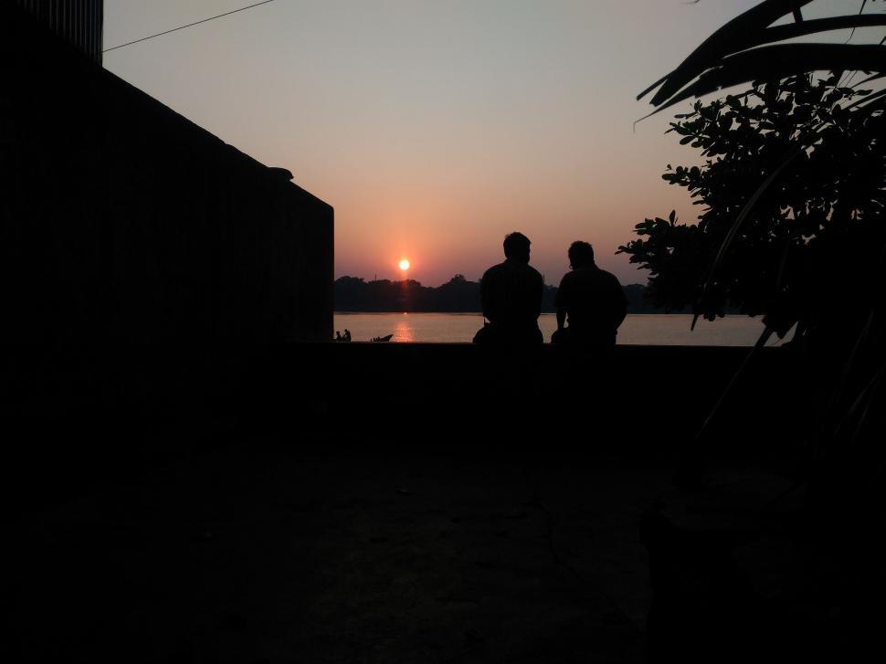 Free Image of Dark View of friends sitting at riverside during sunset  