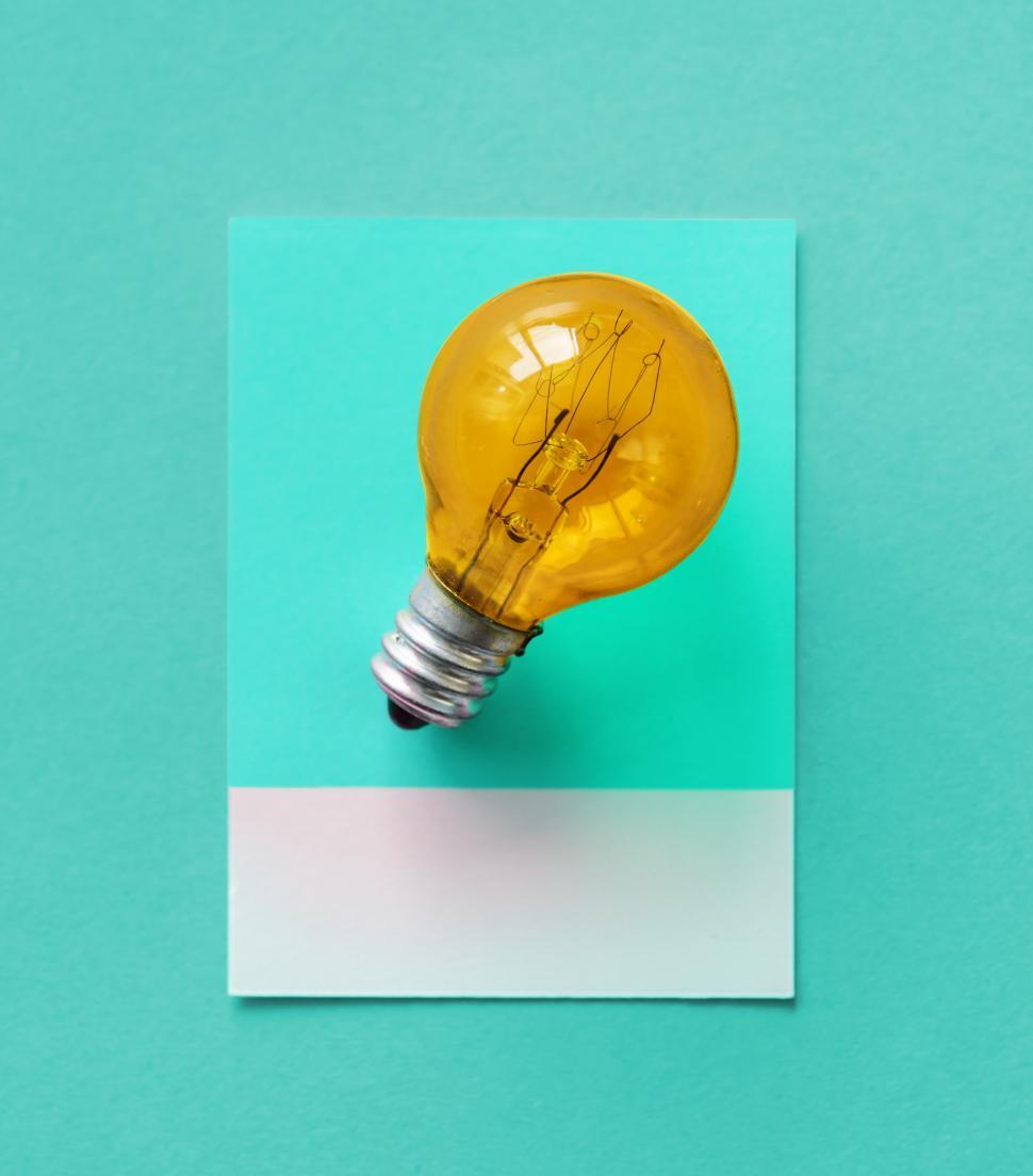 Free Image of Flat lay a small yellow lightbulb on spaced cardboard frame 