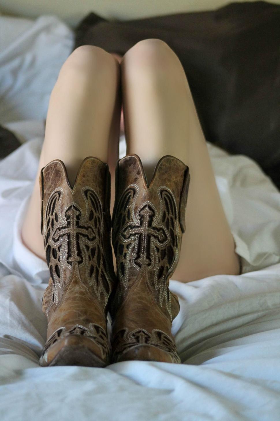 Free Image of Woman in Cowboy Boots on bed 