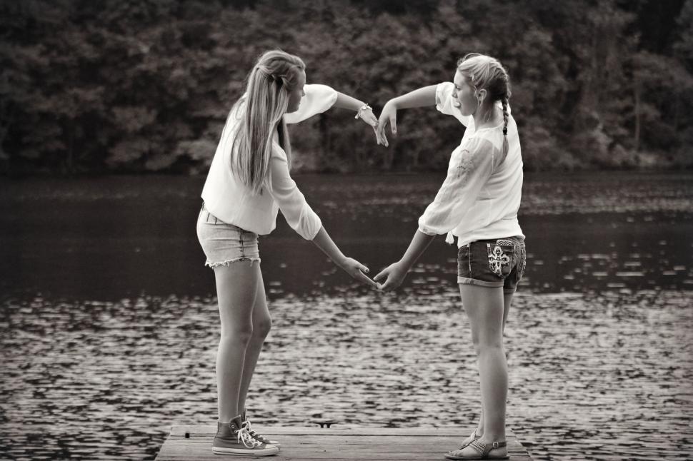 Free Image of Two girlfriends making heart near lake  