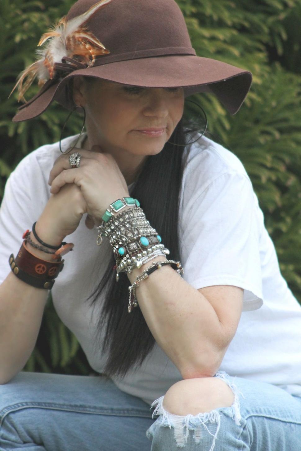 Free Image of Stylish Woman in Brown Floppy Hat Sitting With Folded Hands  