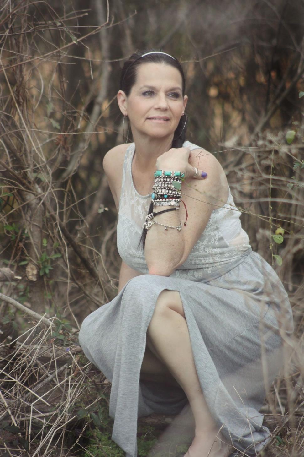 Free Image of Fashionable Woman wearing bracelets sitting amidst trees  