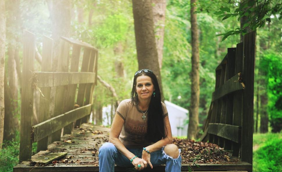 Free Image of Urban Woman With Long Hair Posing on Wooden Bridge in Forest  