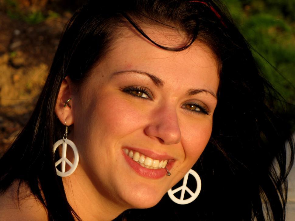 Free Image of Smiling Woman In Peace Sign Earrings 