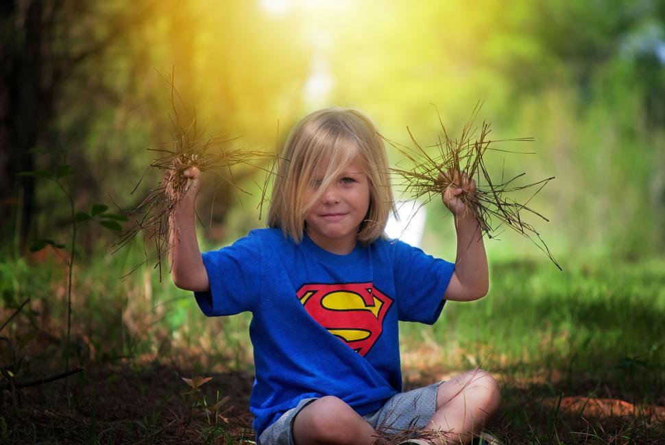Free Image of Little Boy with Blonde Hair Holding Pine Straw in Hands 
