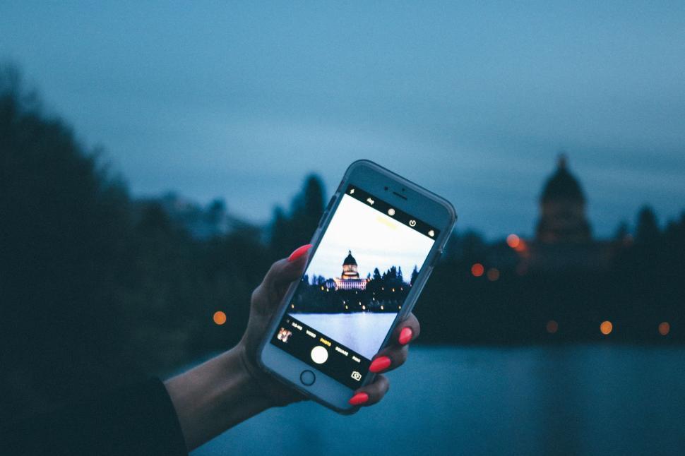 Free Image of Woman taking a picture of Lake and Washington State Capitol with Smartphone  