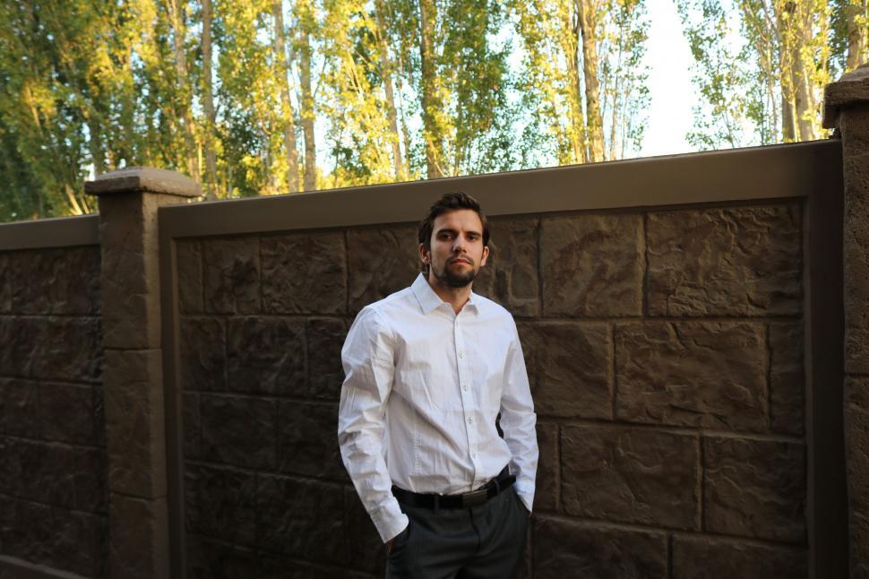 Free Image of Young Businessman with Stone Fence Wall - Looking at camera  