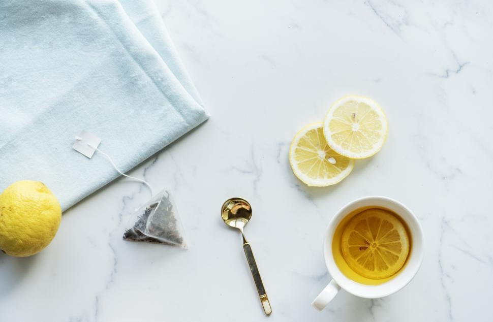 Free Image of Flat lay of a cup of lemon tea on the marble surface with citrus 