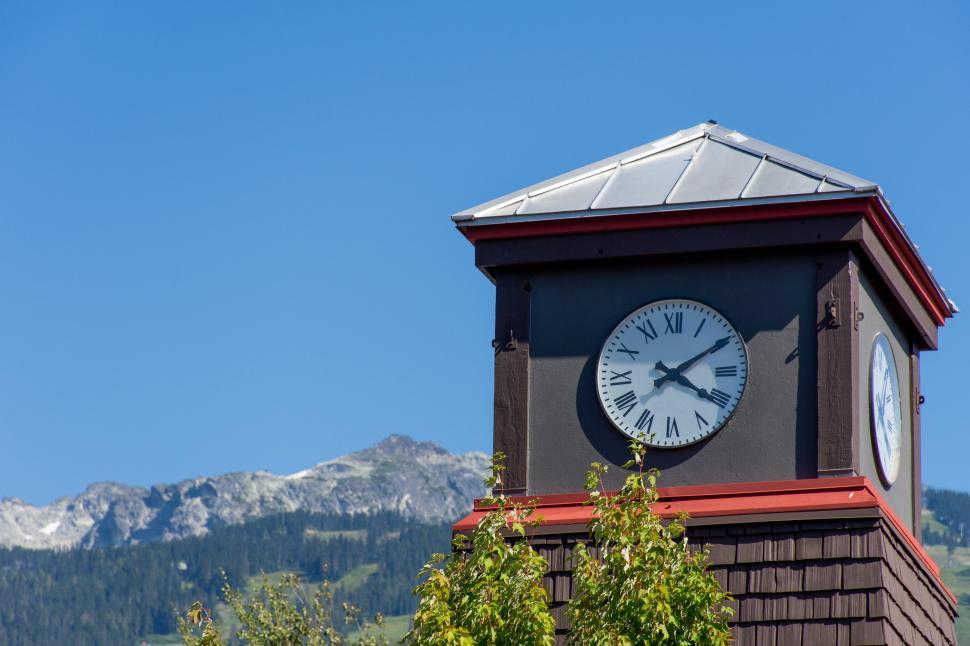Free Image of Roman Numeral Clock Tower with rocky mountains and blue sky 