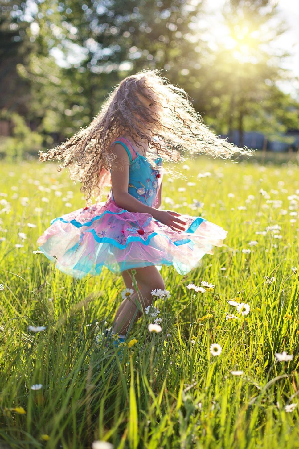 Free Image of Little Girl playing in flower field - looking at camera  