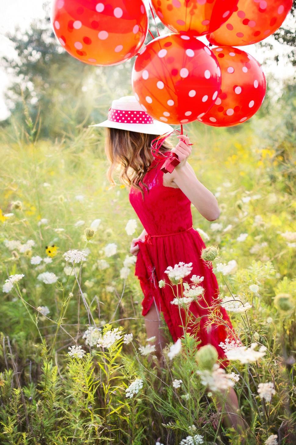 Free Image of Red Dress Woman With Balloons in White Daisy Field 
