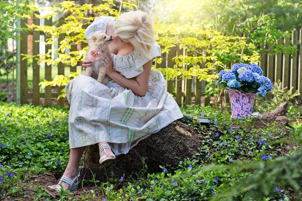 Free Image of Woman Sitting With Pomeranian Dog in the garden  