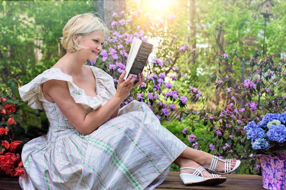 Free Image of Blonde Woman sitting on bench with book in the park 
