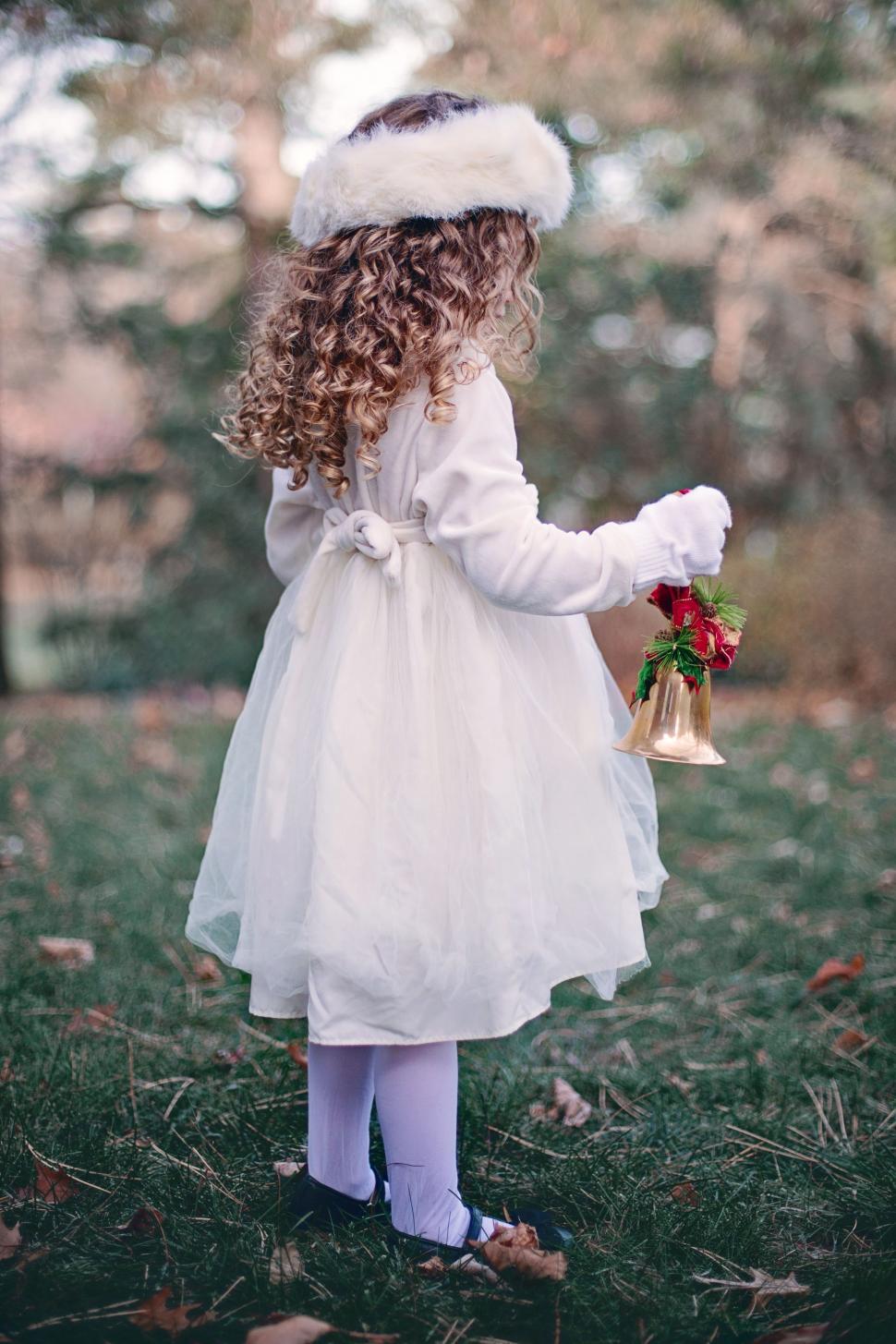 Free Image of Little Girl Standing With Christmas Bell 