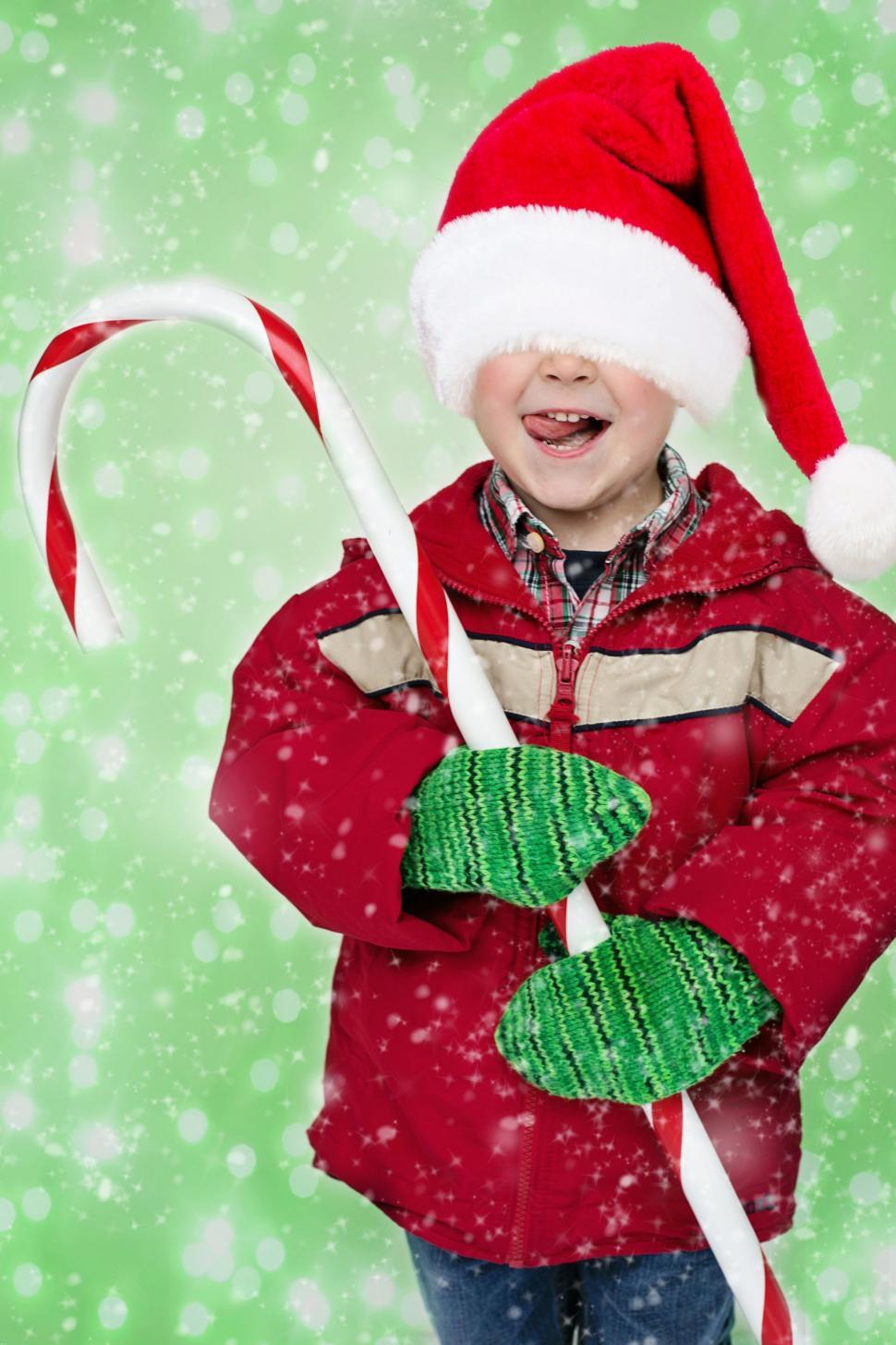 Free Image of Little Boy in Oversized Santa Hat - Snowy Green Background  