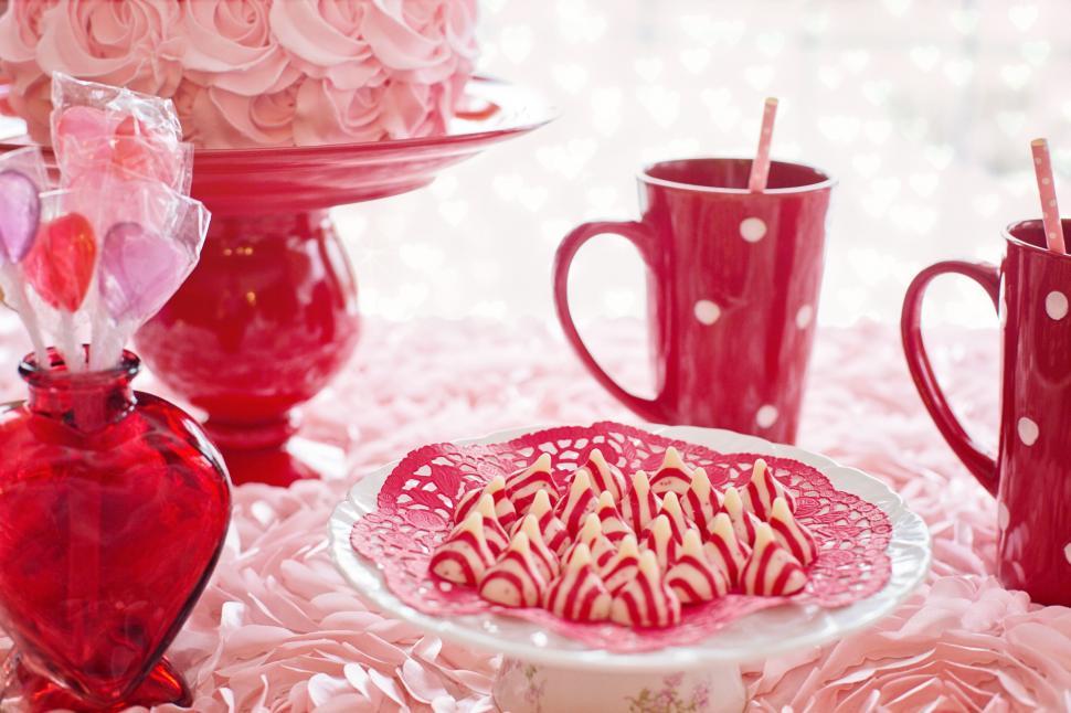 Free Image of Two Red Coffee Mugs and Striped Candies With Pink Flowers 