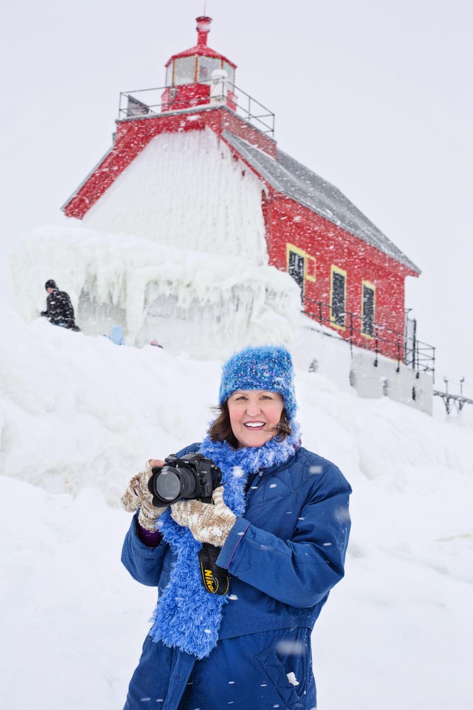Free Image of Female Photographer and Lighthouse in Snowfall - Looking at camera  