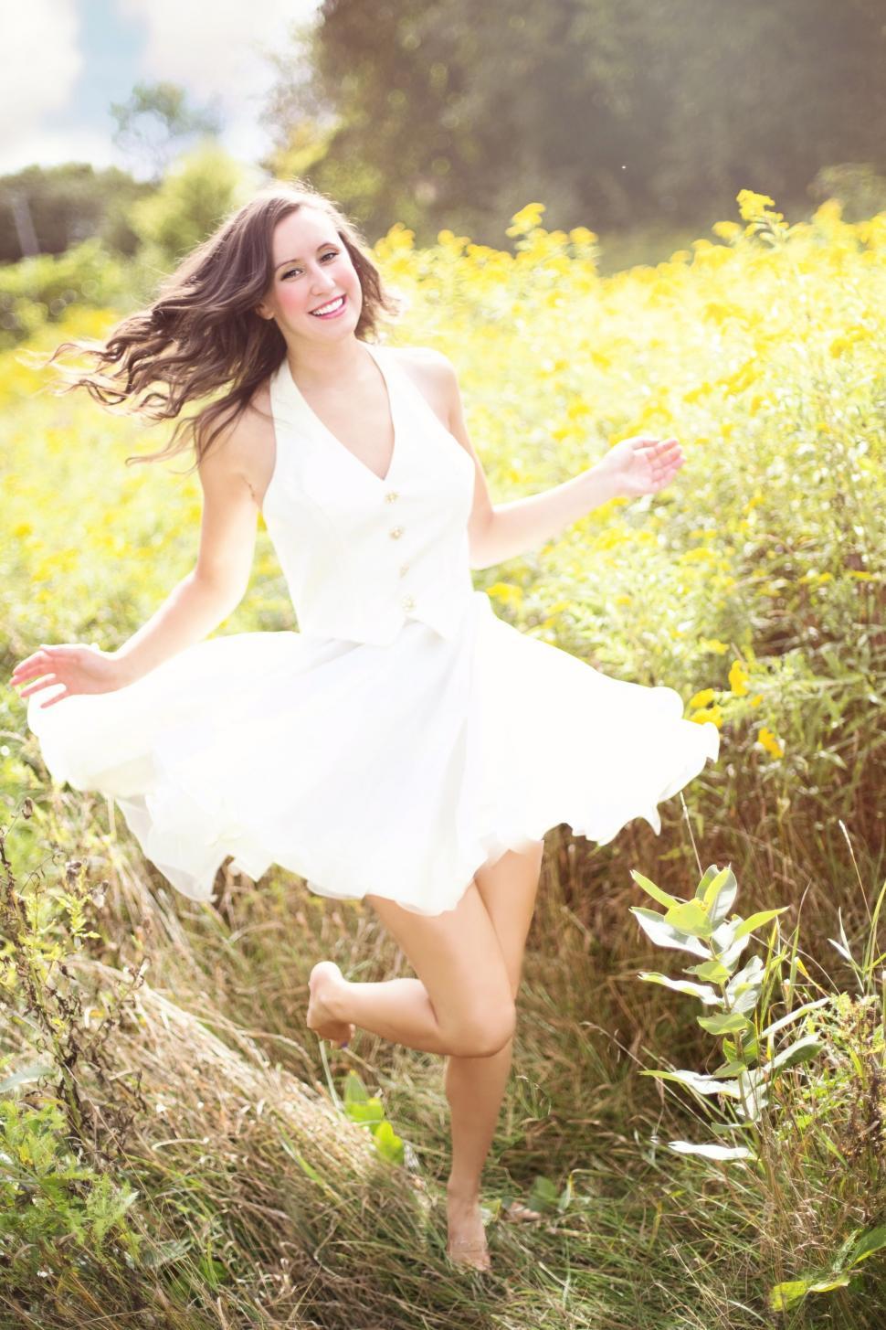 Free Image of Woman with brunette hair dancing in the wildflower field - looking at camera 