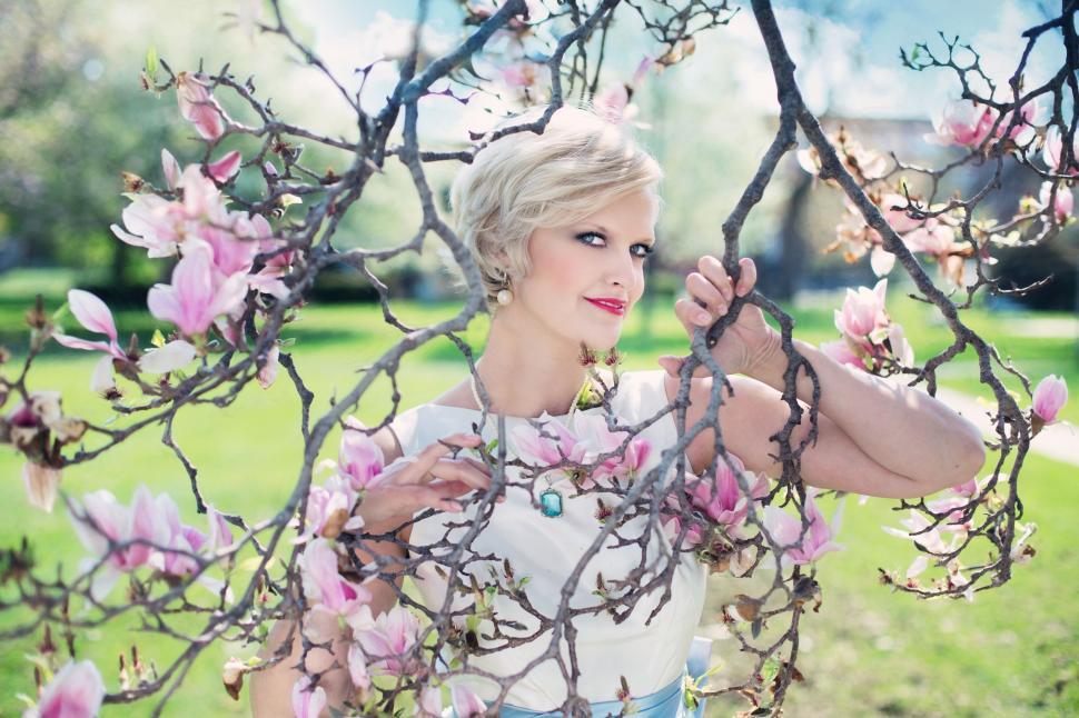 Free Image of Smiling Blonde Woman and Tree Branches With Pink Flowers 