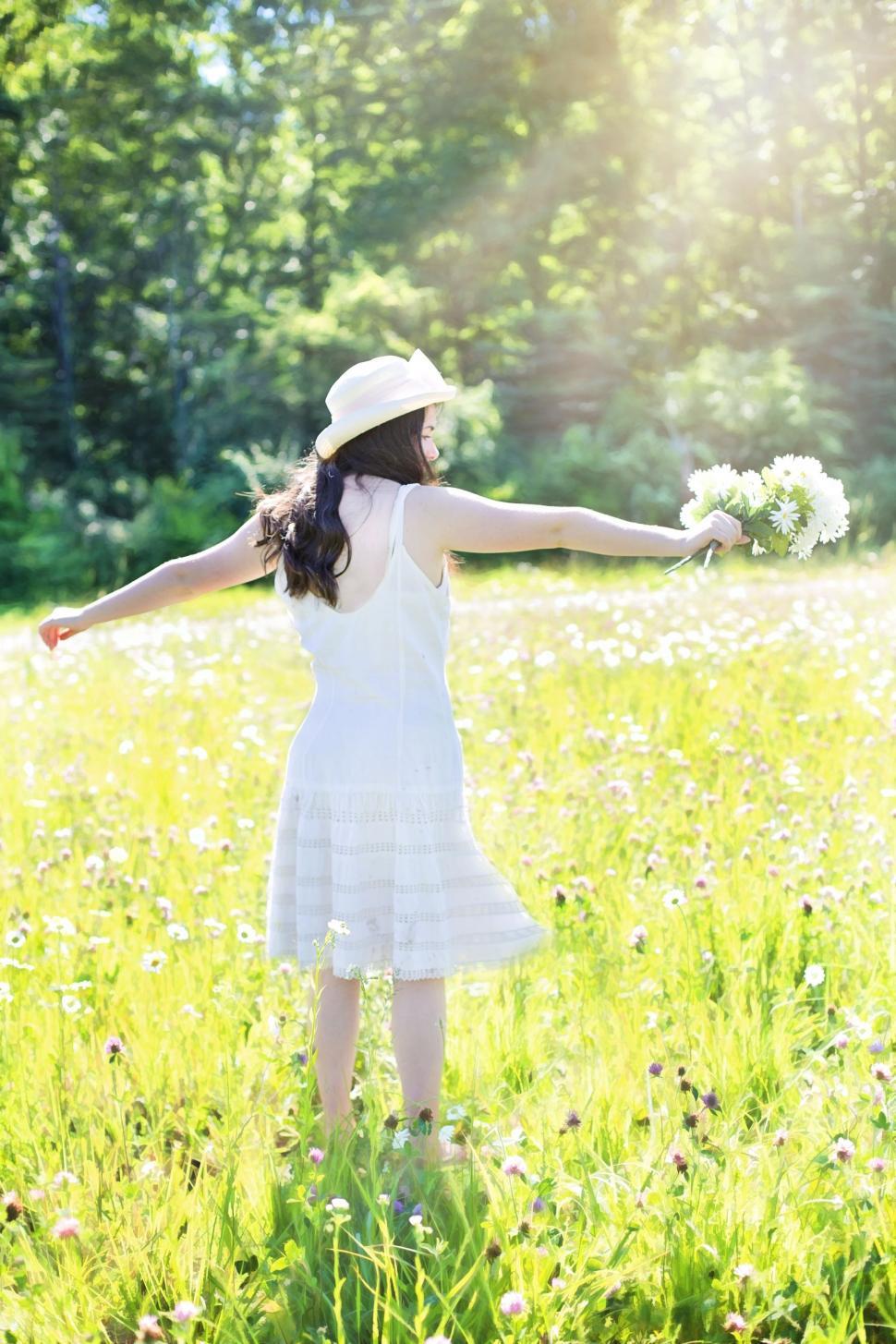 Free Image of Back view of woman in white hat in wild flower field  