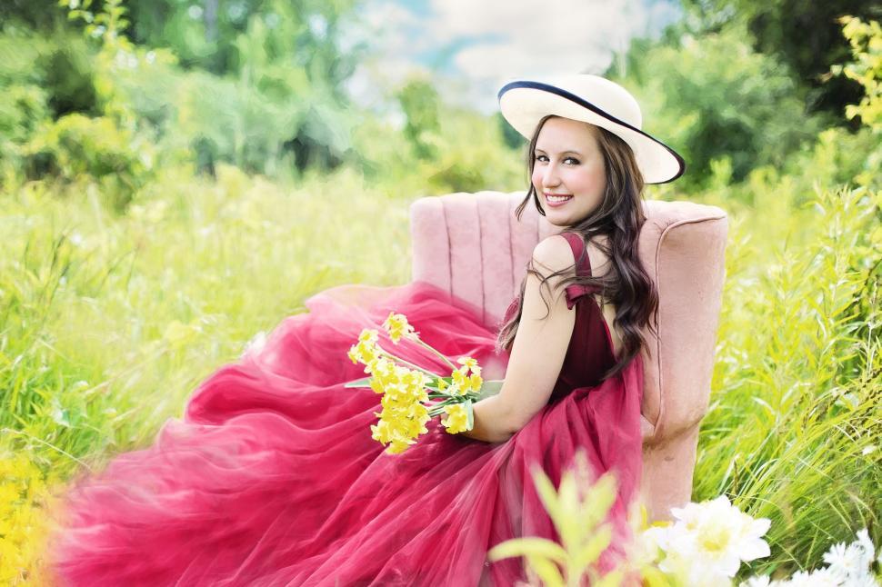 Free Image of Smiling Woman in hat on chair in the meadow - looking at camera 