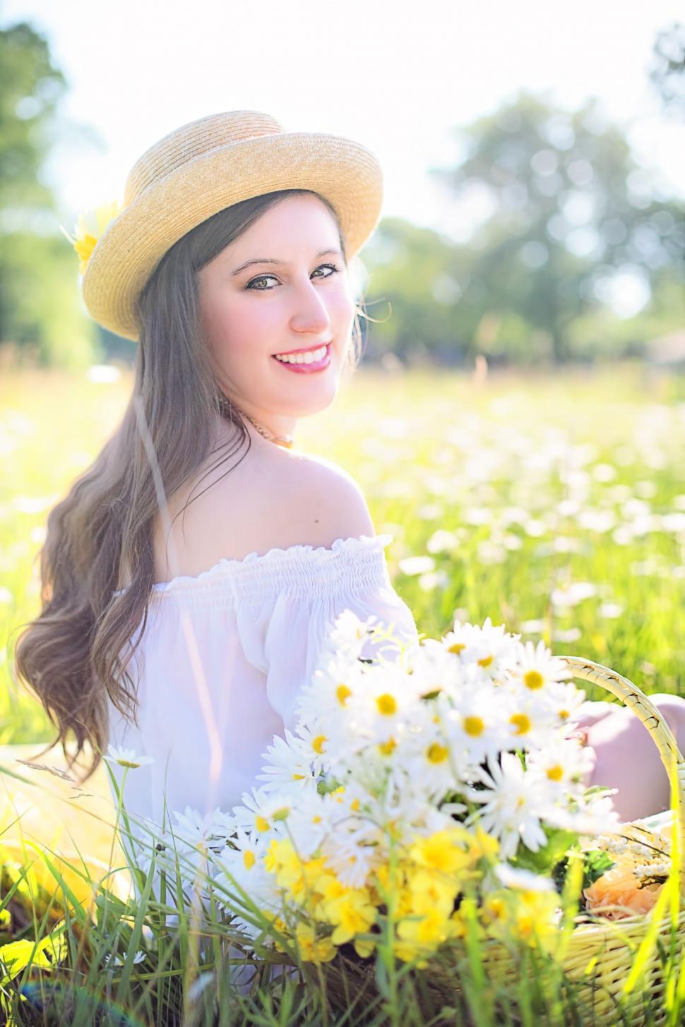 Free Image of Young smiling woman sitting in white flower field  