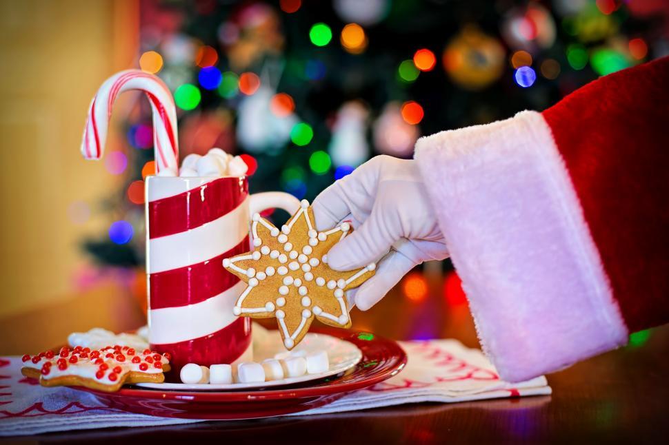 Free Image of Santa Hand and Coffee Mug with Star Shaped Cookies on Plate 