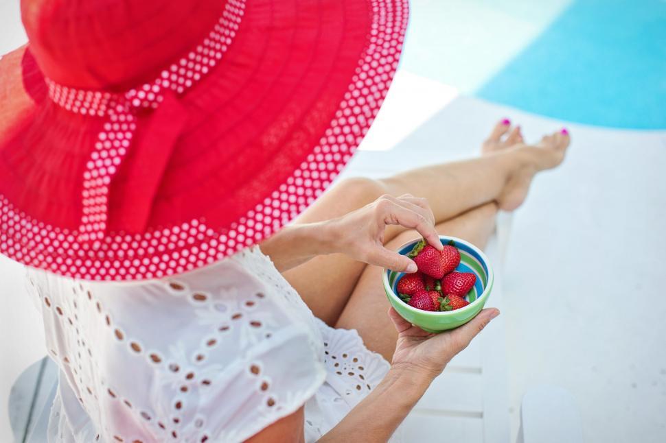 Free Image of Woman in hat with strawberries at poolside 