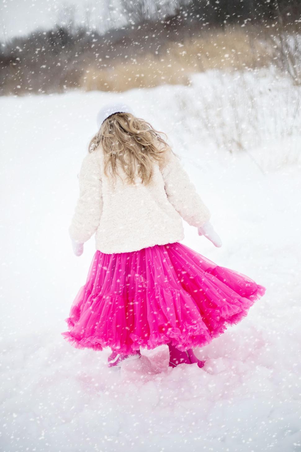 Free Image of Back view of Little Girl with blonde hair and white fur jacket in snow 