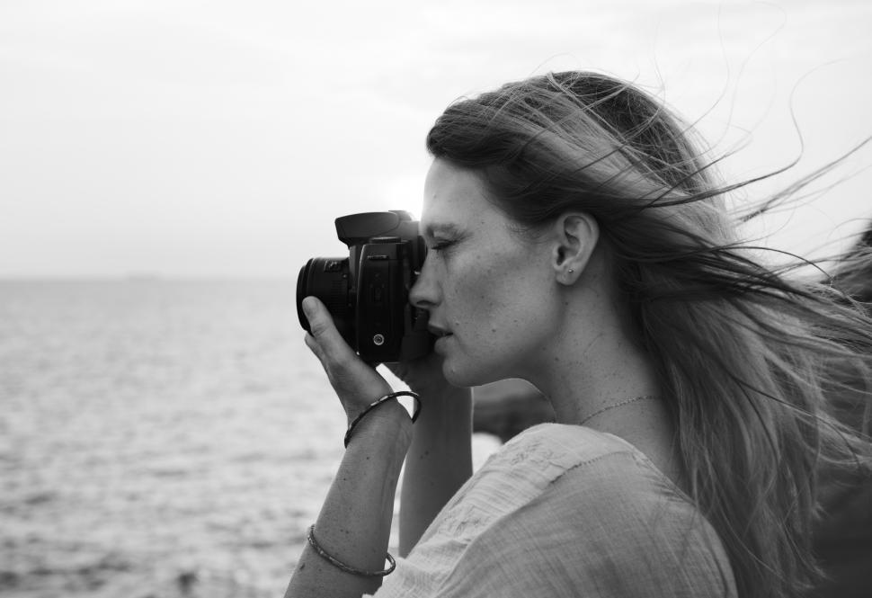 Free Image of Side view of a young woman taking photograph - black and white 