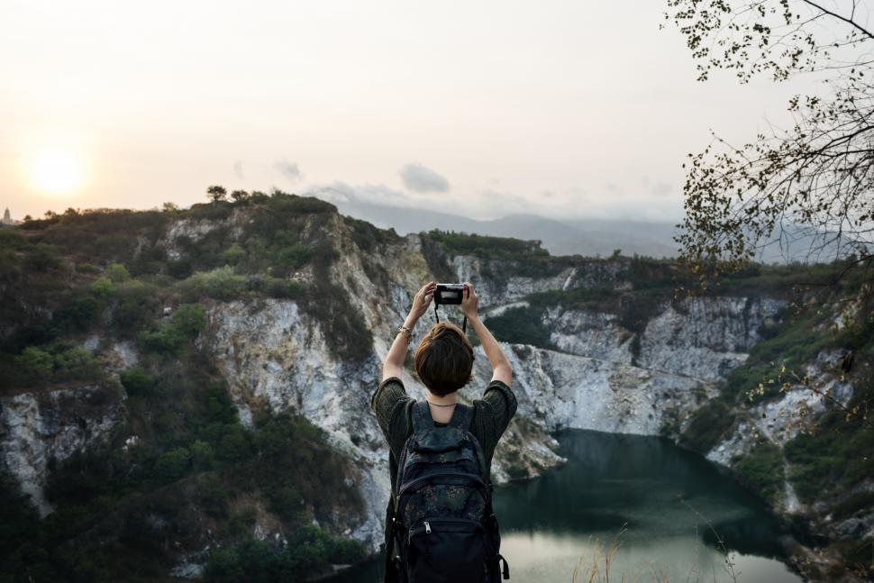 Free Image of View of a young woman holding a camera to take a landscape photo 