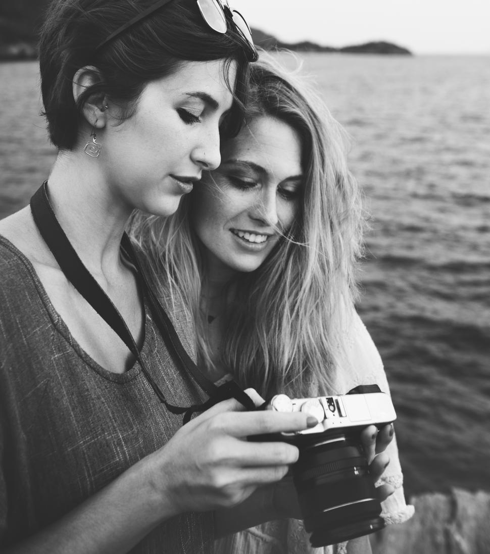 Free Image of Two young caucasian women looking at their photograph on the camera display by the sea 