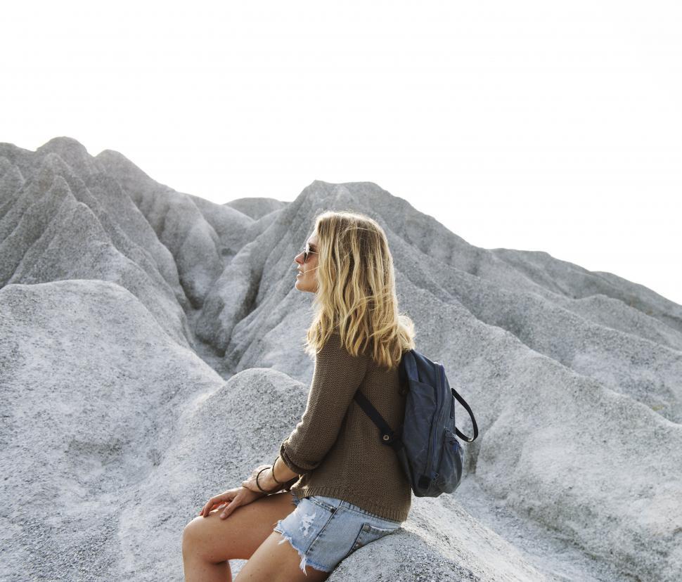 Free Image of A young caucasian woman sits on a rock 