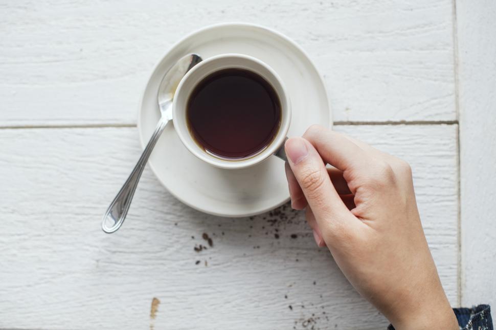 Free Image of Overhead view of a hand holding a cup of coffee 