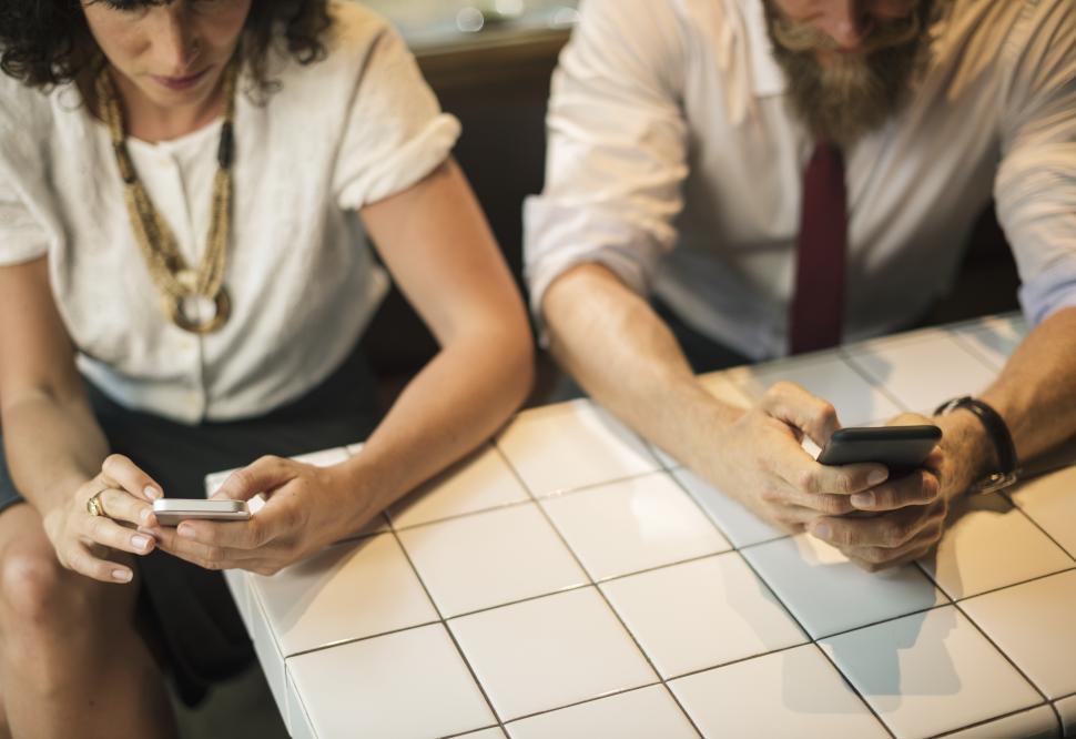Free Image of Two business people at a restaurant table looking at mobile phones 