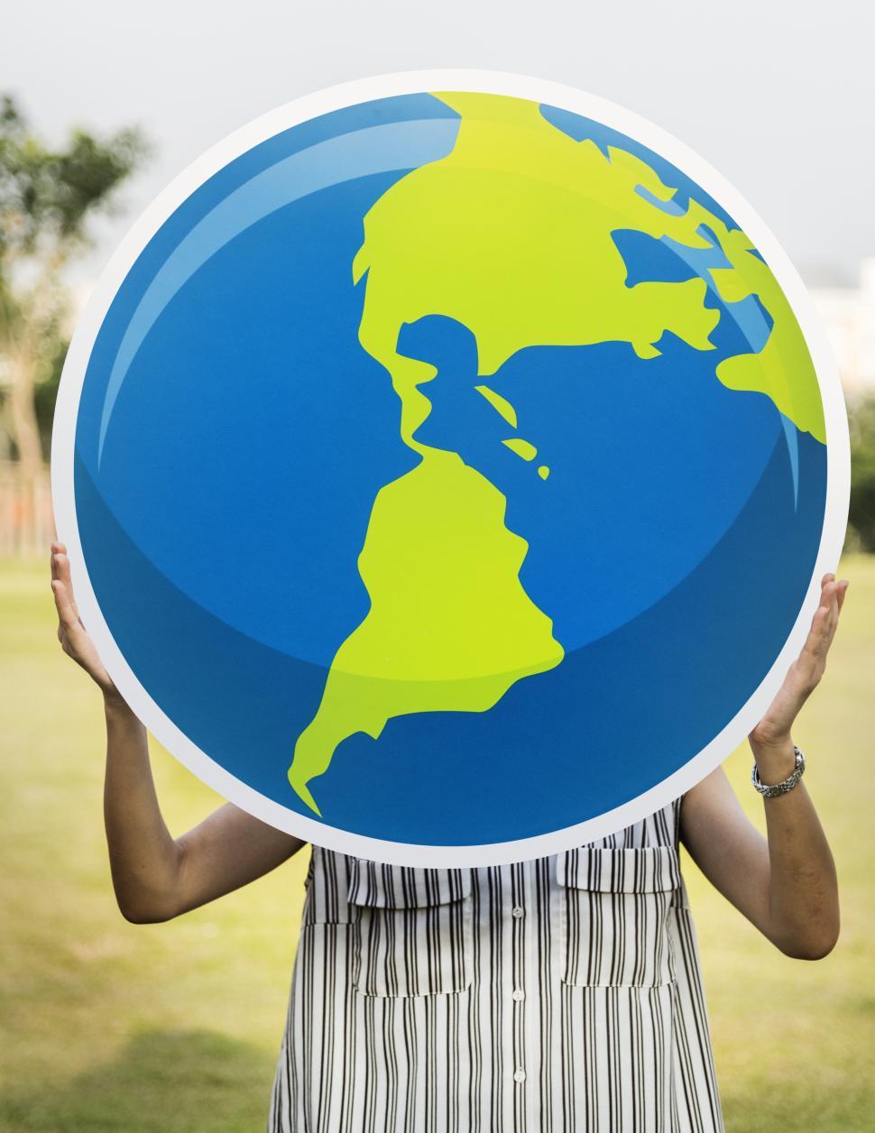 Free Image of A woman holding a globe shaped cardboard cutout in front of face 