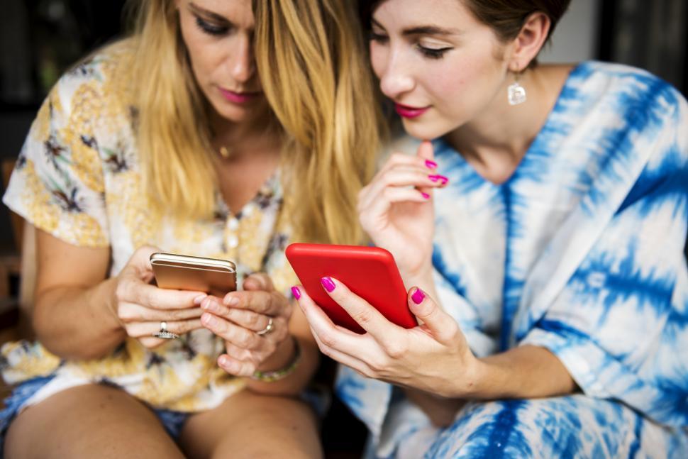 Free Image of Two young women posing with their mobile phones, social media concept 