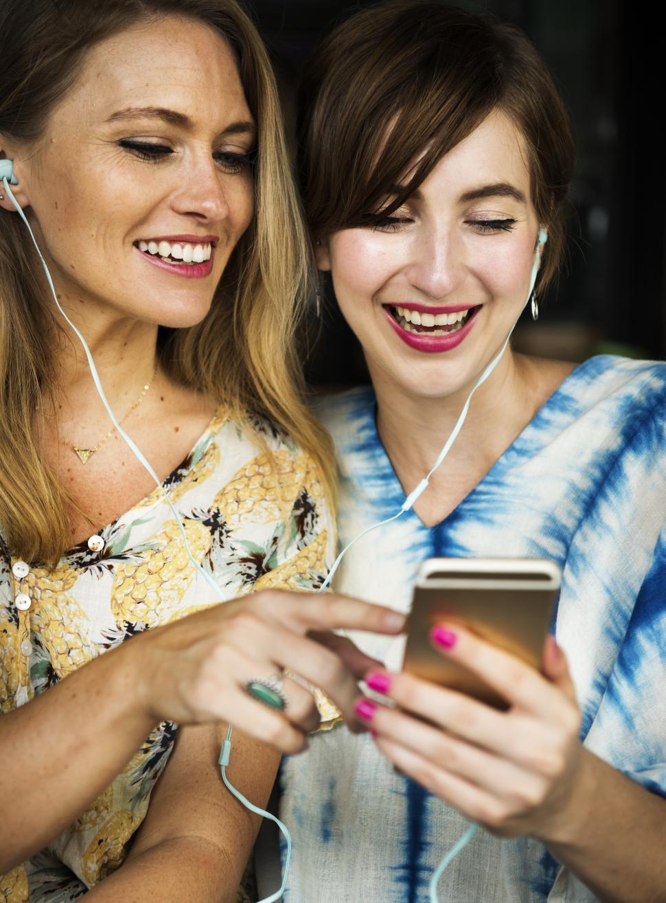 Free Image of Two young Caucasian women listening to music on the mobile phone 