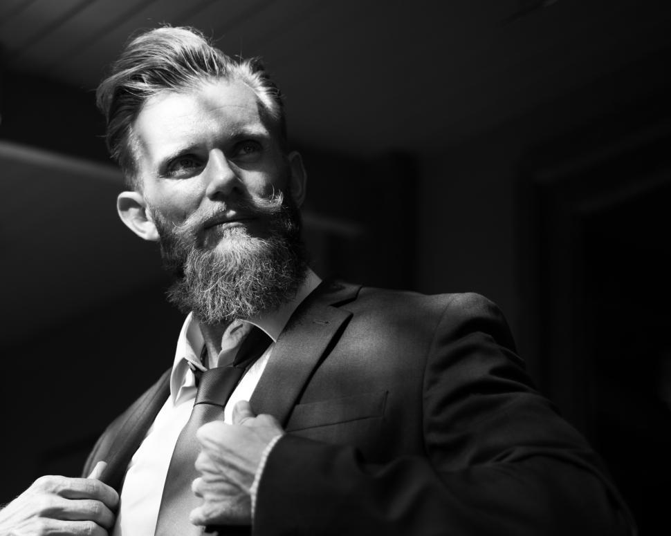 Free Image of A bearded man posing with his arms holding his suit jacket 