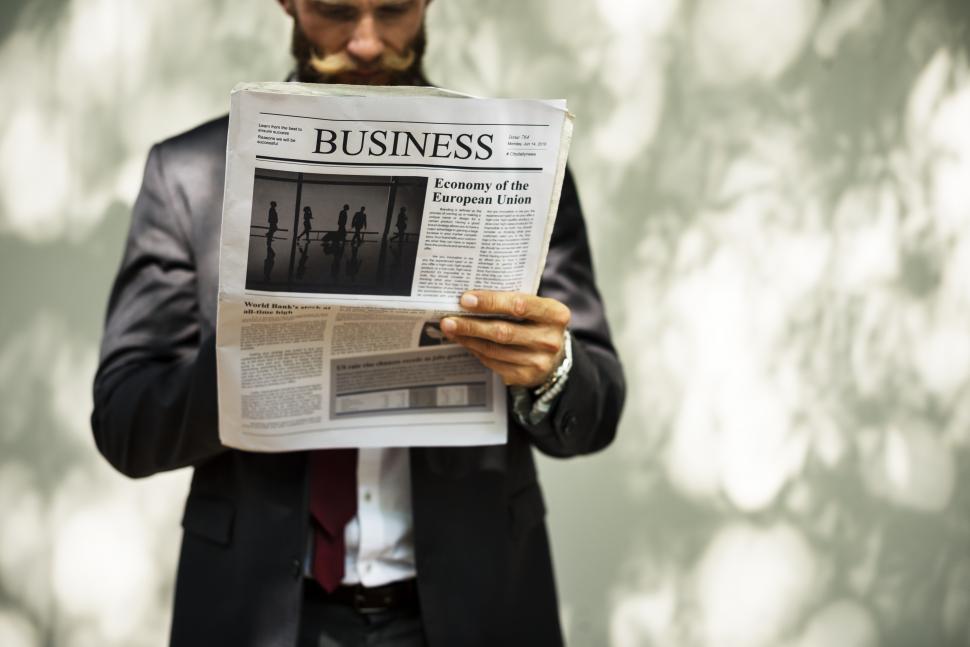 Free Image of A bearded man reading the business section of a newspaper 