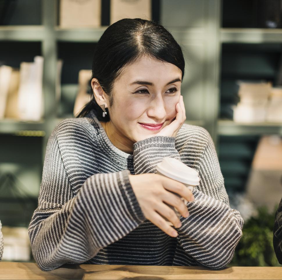 Free Image of A woman in a striped sweater enjoying coffee at a cafe 