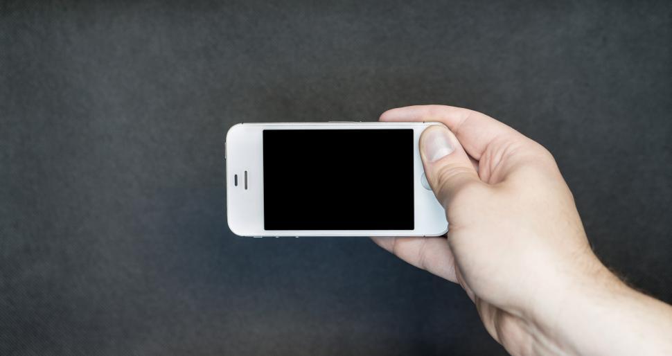 Free Image of A hand posing with a smartphone on dark background 