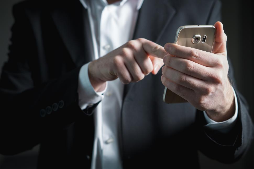 Free Image of Close up of a business person looking at mobile phone in his hand 
