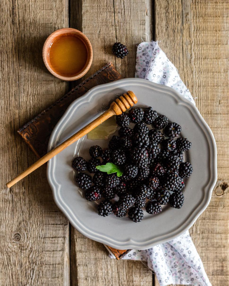 Free Image of Overhead view of blackberries and honey in a ceramic plate 