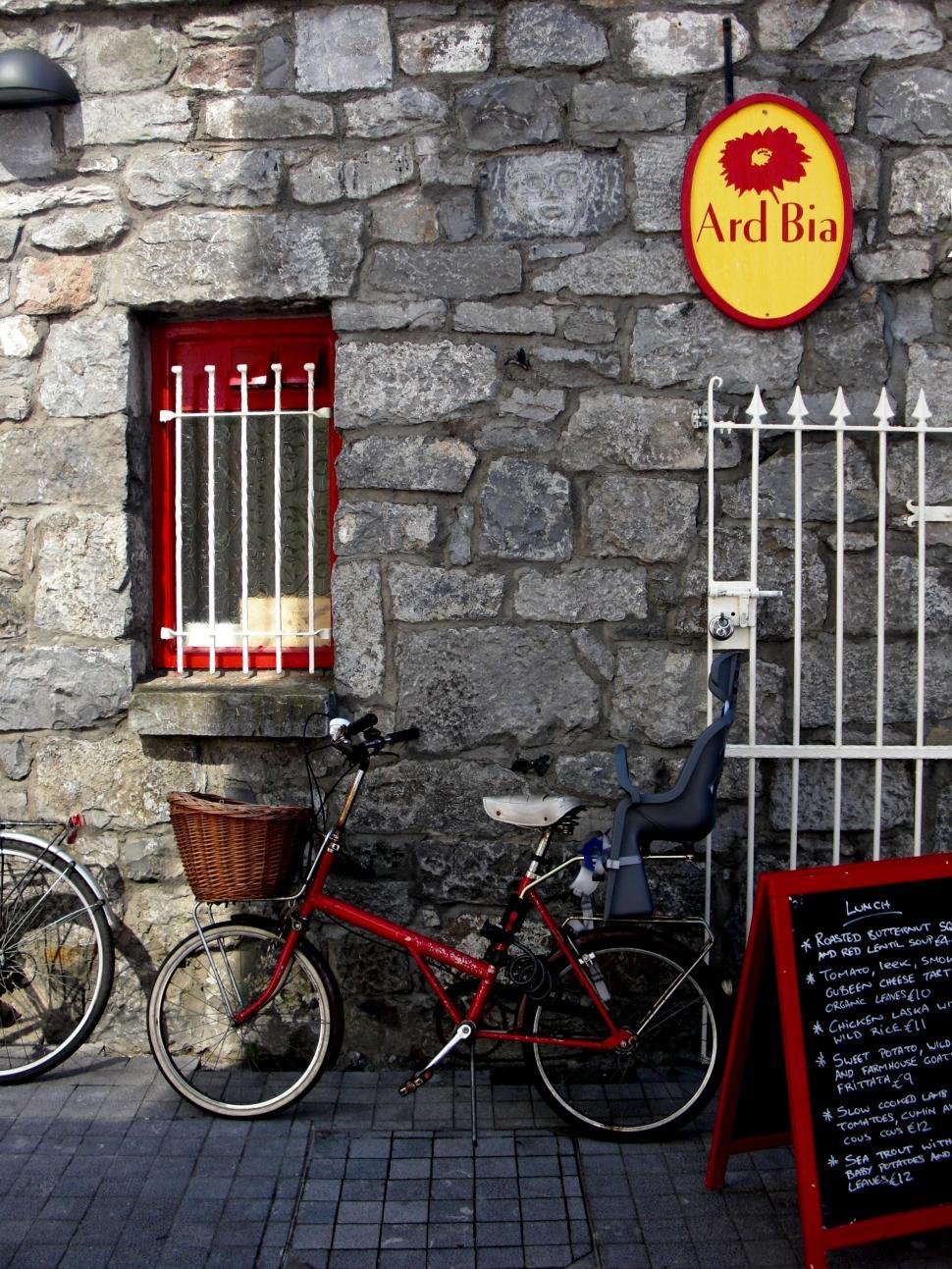 Free Image of Red Bike Parked Next to Stone Building 