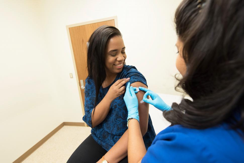Free Image of Healthcare worker putting on a bandaid after a shot 
