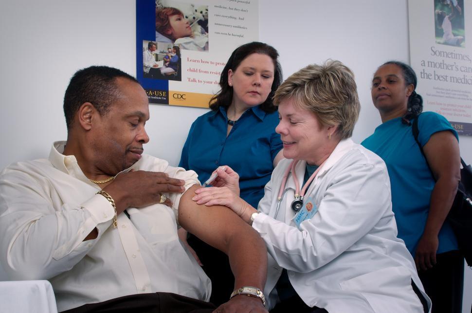 Free Image of Group of Healthcare Providers Looking on as a Man is Immunized 